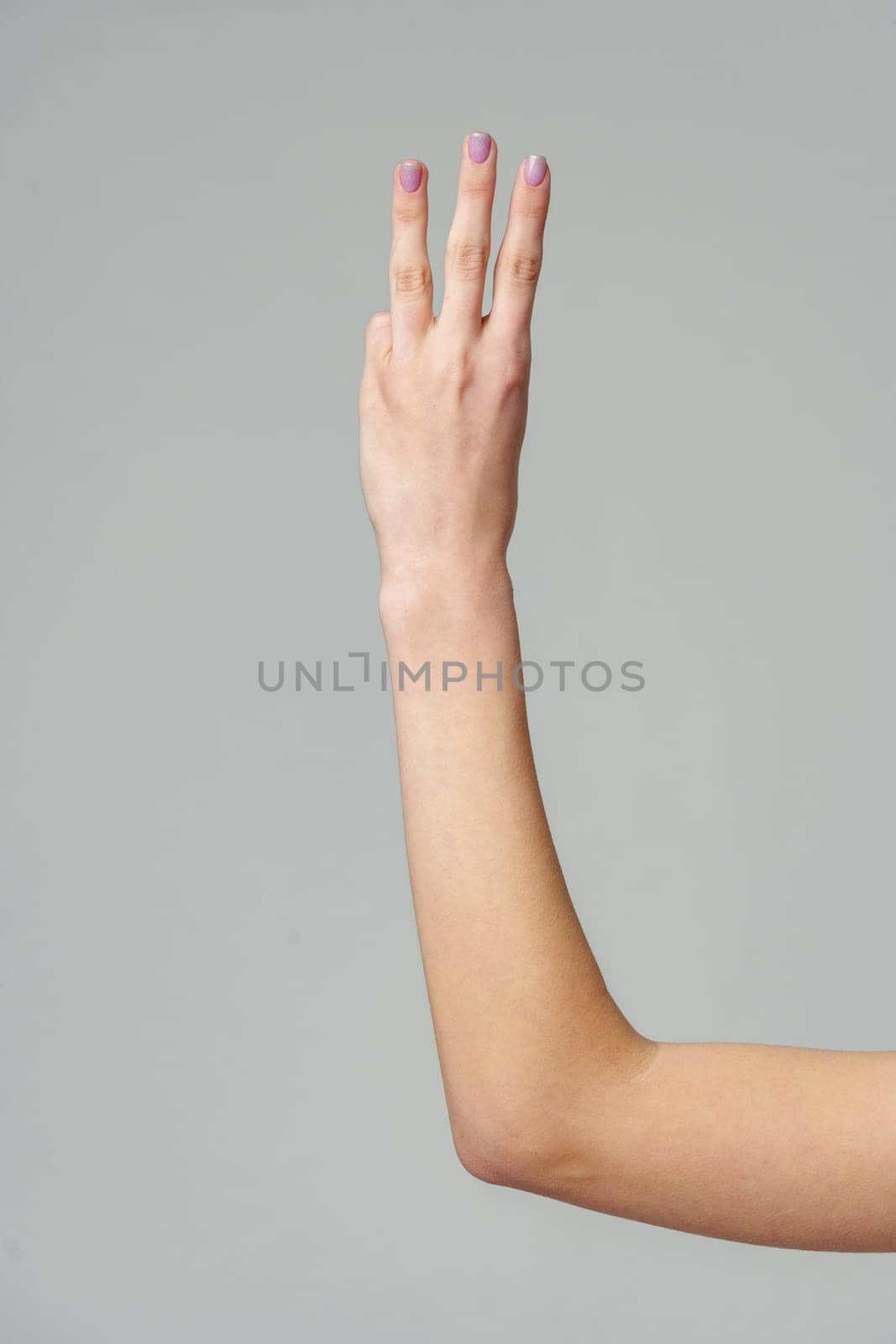 Female hand gesturing numbers on gray background close up