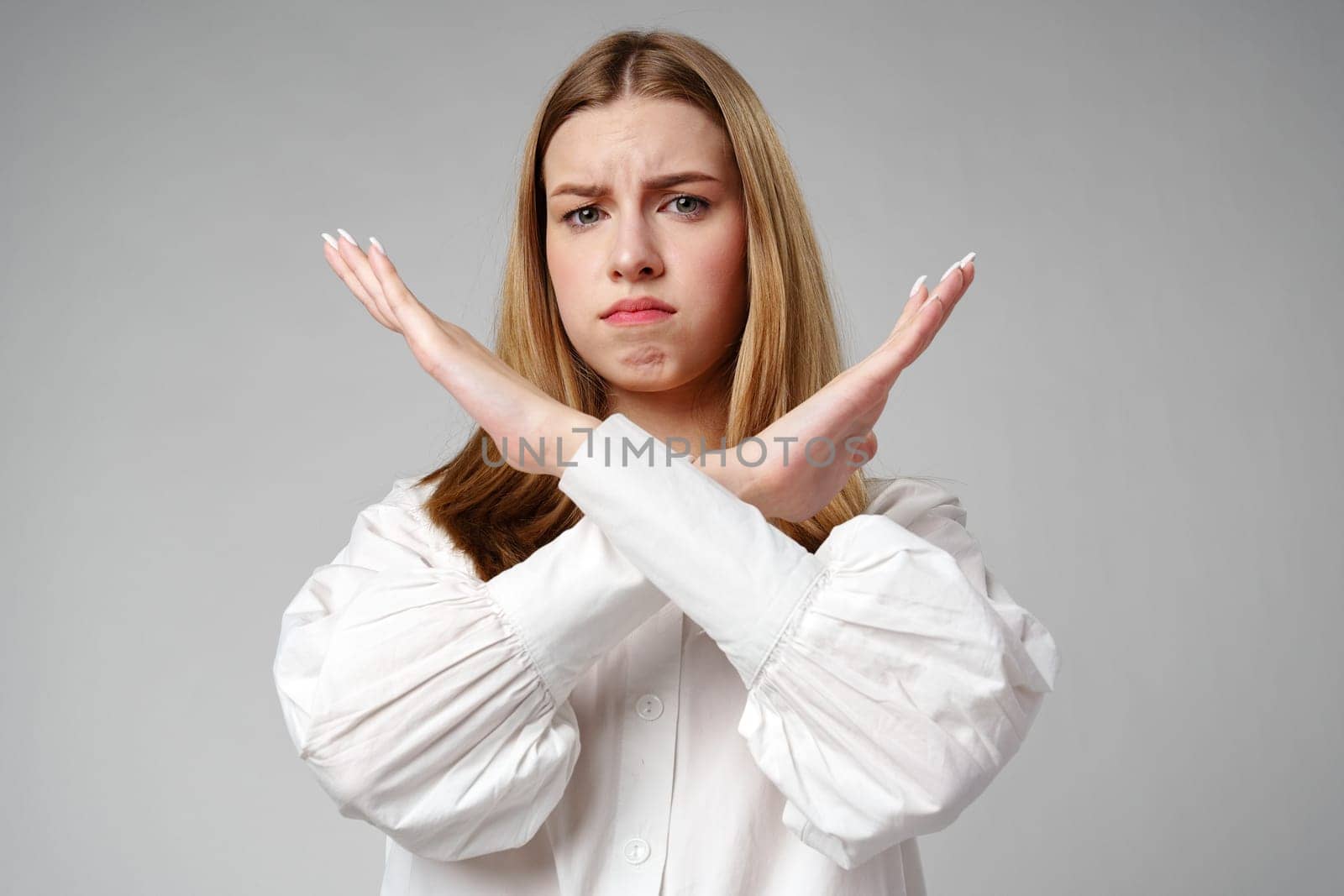 oung Woman Making X Sign With Arms to Express Prohibition or Disagreement in studio