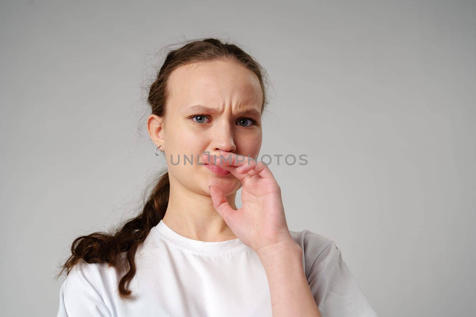 Young Woman Making Funny Face With Her Fingers on gray background close up