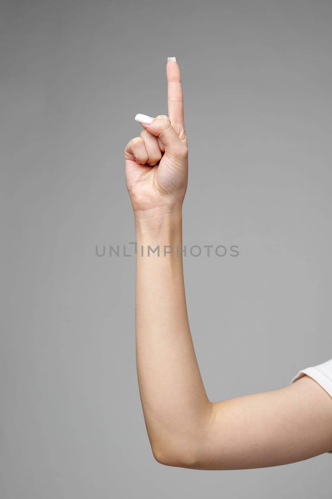Female hand gesturing sign against gray background close up