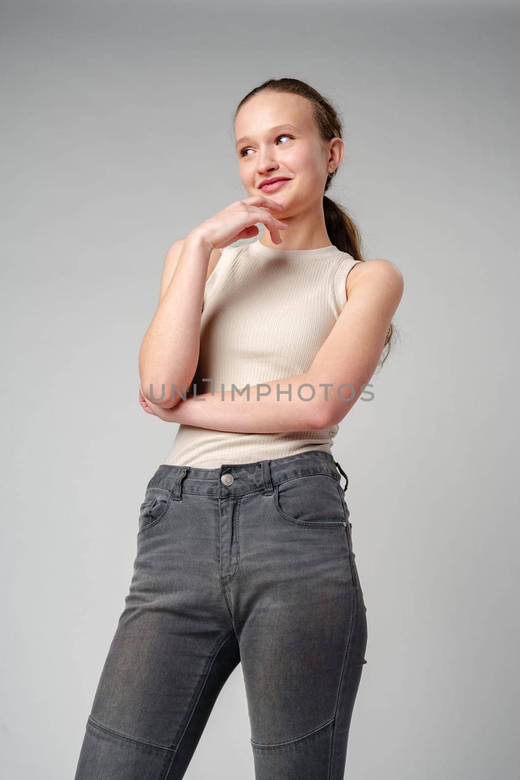 Girl in Beige Tank Top and Grey Jeans on gray background by Fabrikasimf