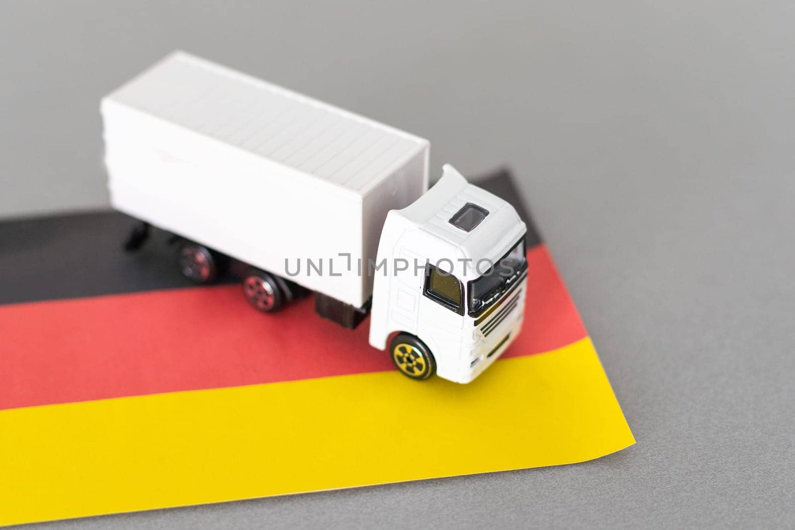 Mini toy at table with blurred background. Industrial shipping concept. toy truck, germany flag by Andelov13