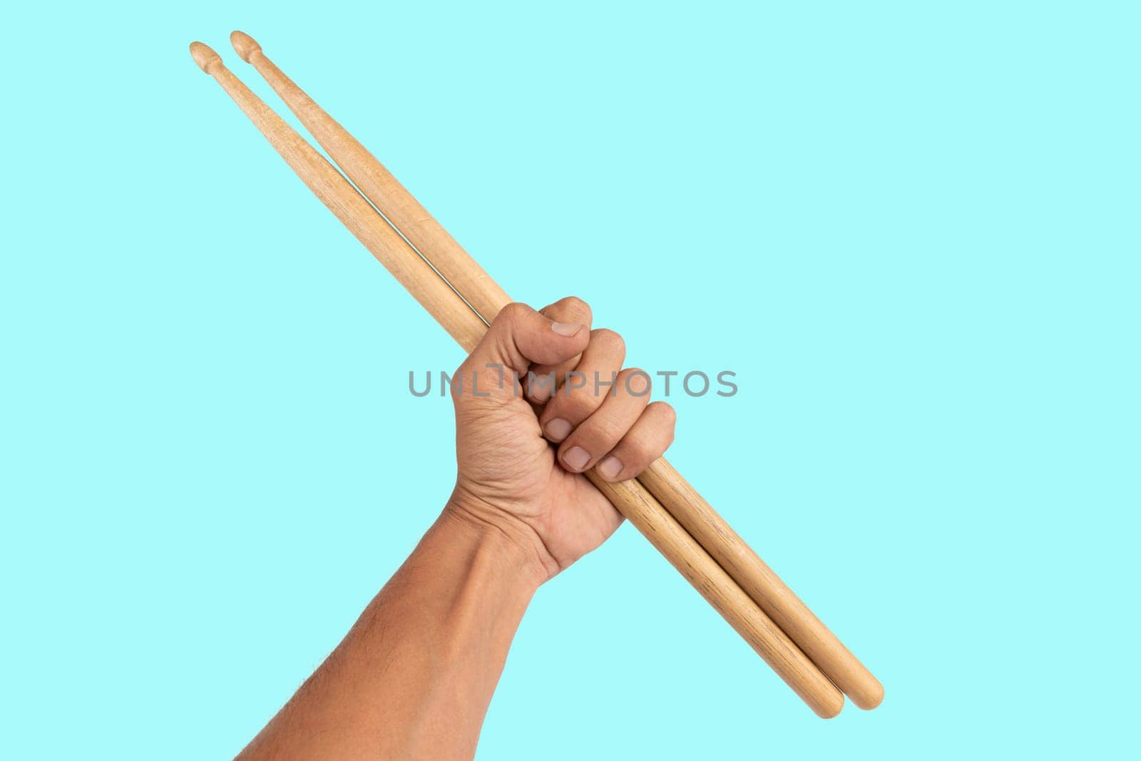 Black male hand holding wooden Drum sticks isolated on cyan background by TropicalNinjaStudio