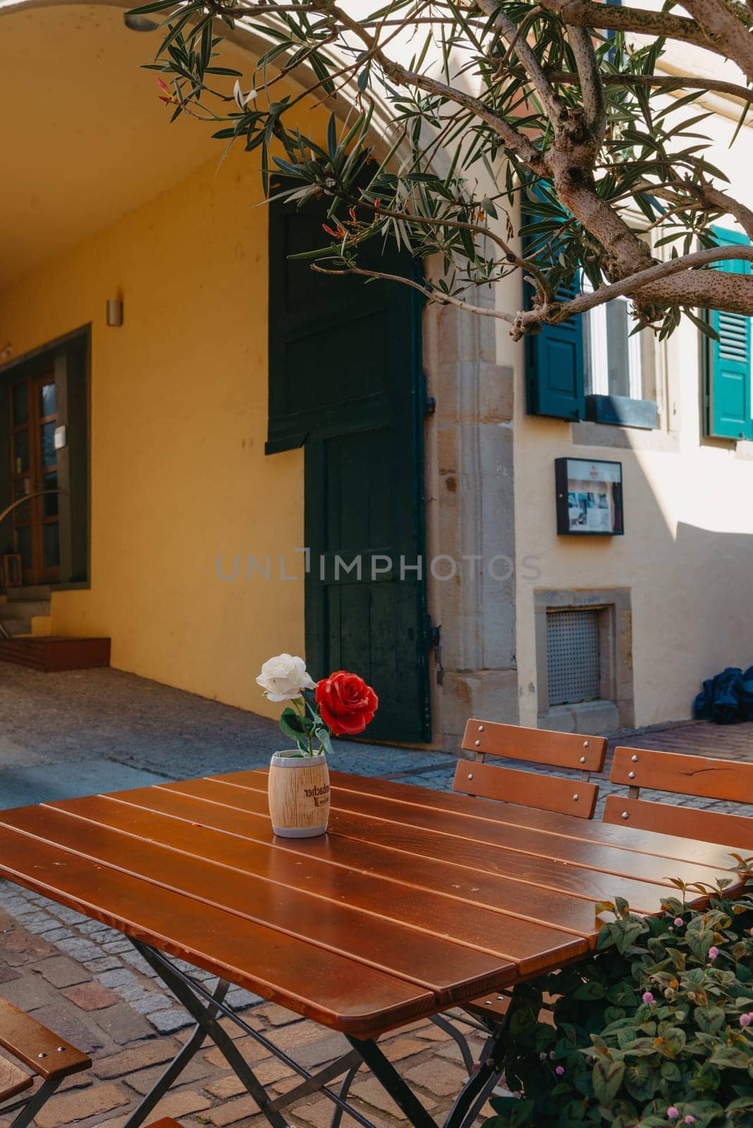 Empty cafe terrace with white table and chair. exterior of the cafe restaurant. interior Street cafe. Cozy street with flowers and French-style cafe table. Decor facade of coffeehouse with bike. Table on a summer terrace with cake and teapot. Garden table and chairs