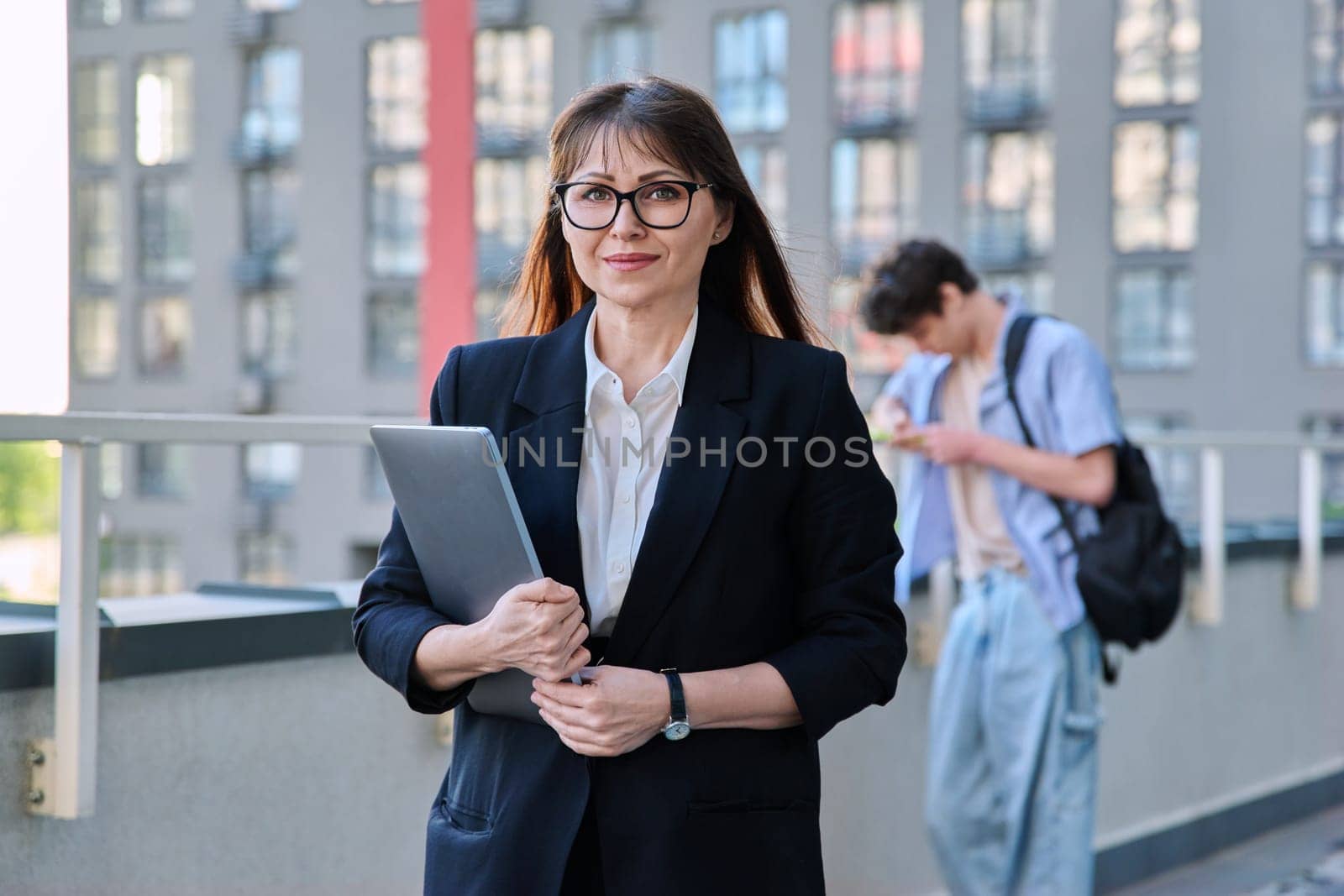 Business mature woman entrepreneur blogger broker agent consultant with laptop outdoor, modern city building background. Business, work, technology, urban lifestyle concept