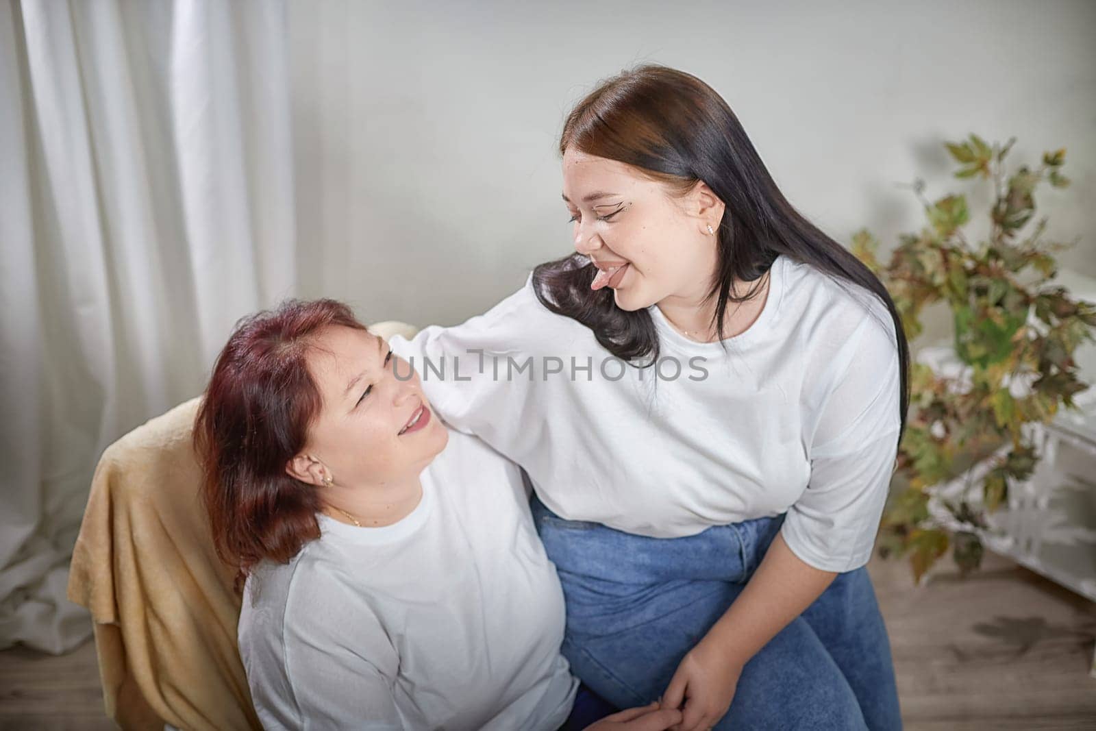 Happy Overweight family with mother and daughter in room. Middle aged woman and teenager girl having fun, joy and hugging
