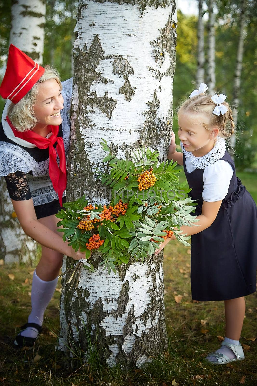 Young and adult schoolgirl on September 1, mother and daughter having fun and joy. Generations of schoolchildren of USSR and Russia. Female pioneer in red tie and October girl in modern uniform