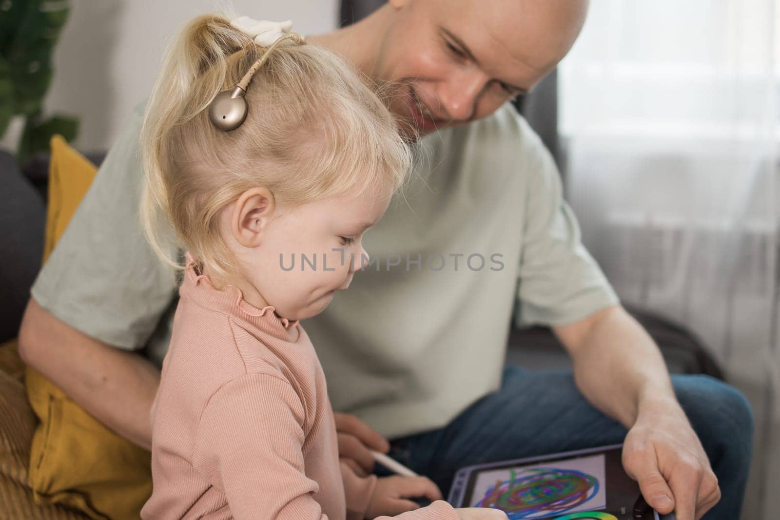 Close-up Deaf child girl with cochlear implant studying to hear sounds and have fun with father - recovery after cochlear Implant surgery and rehabilitation concept by Satura86