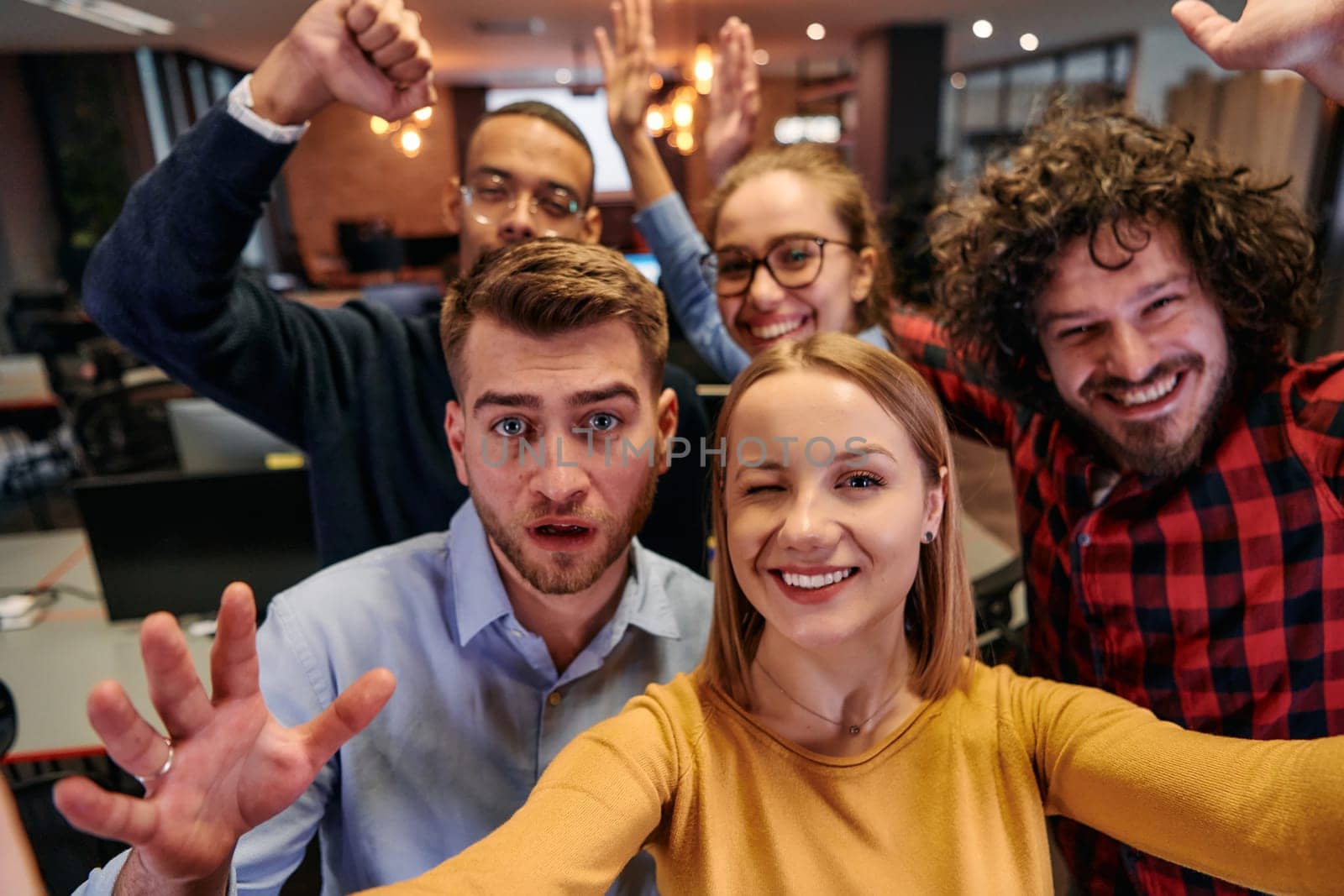 A diverse group of business professionals take a break from their tasks in a modern startup office to capture a creative selfie, showcasing teamwork and a vibrant workplace culture by dotshock