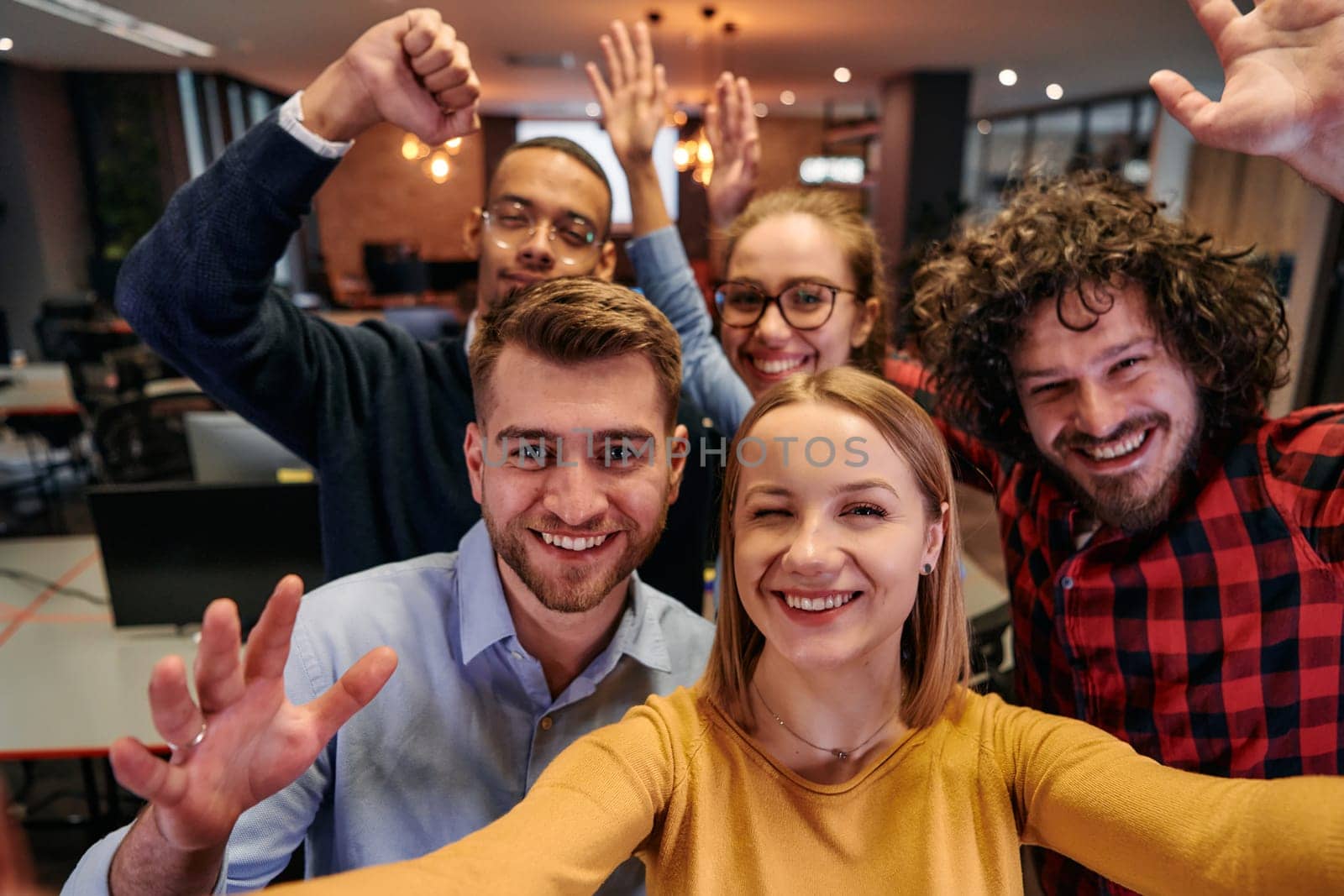 A diverse group of business professionals take a break from their tasks in a modern startup office to capture a creative selfie, showcasing teamwork and a vibrant workplace culture by dotshock