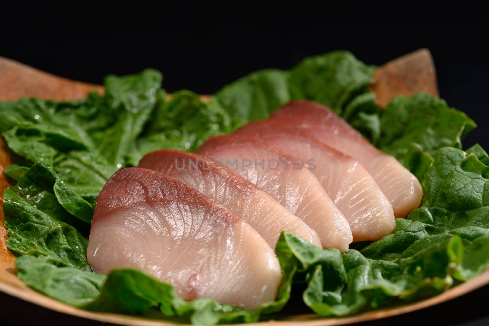 Fresh raw Hamachi sashimi or yellowtail fish served on wooden plate. Traditional Japanese food.