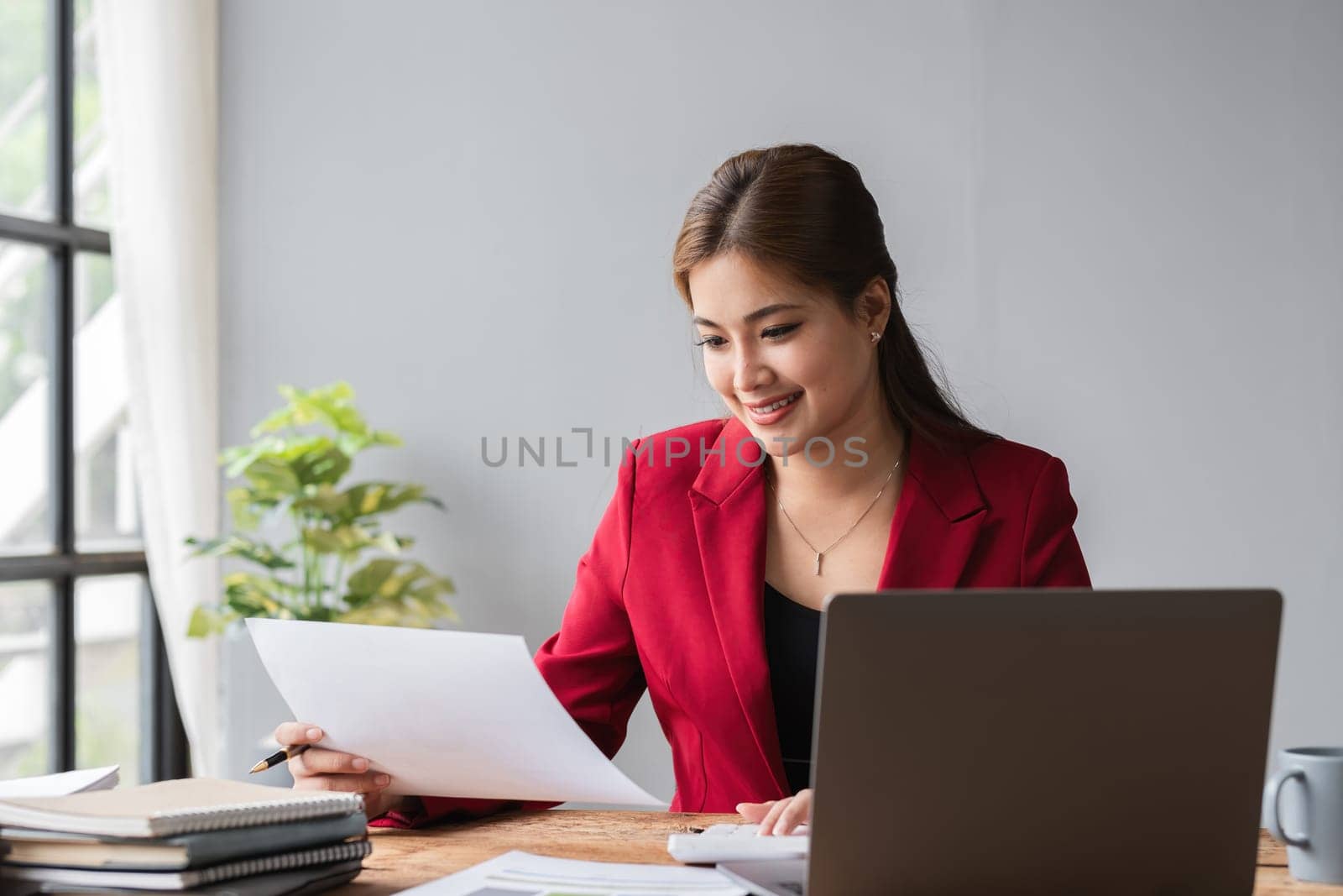 Beautiful accountant sitting working with laptop calculating financial and tax figures for company on desk in living room..