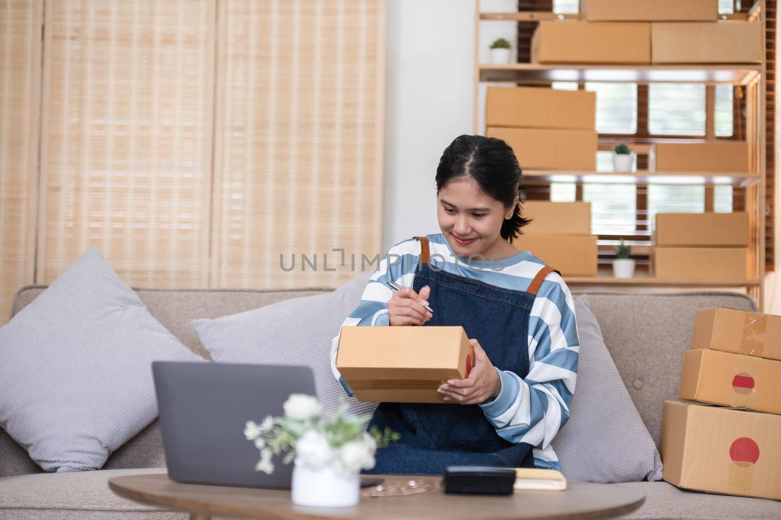 entrepreneurs small business Write shipping information on a cardboard box in home office. Small business operators preparing to ship to customer.