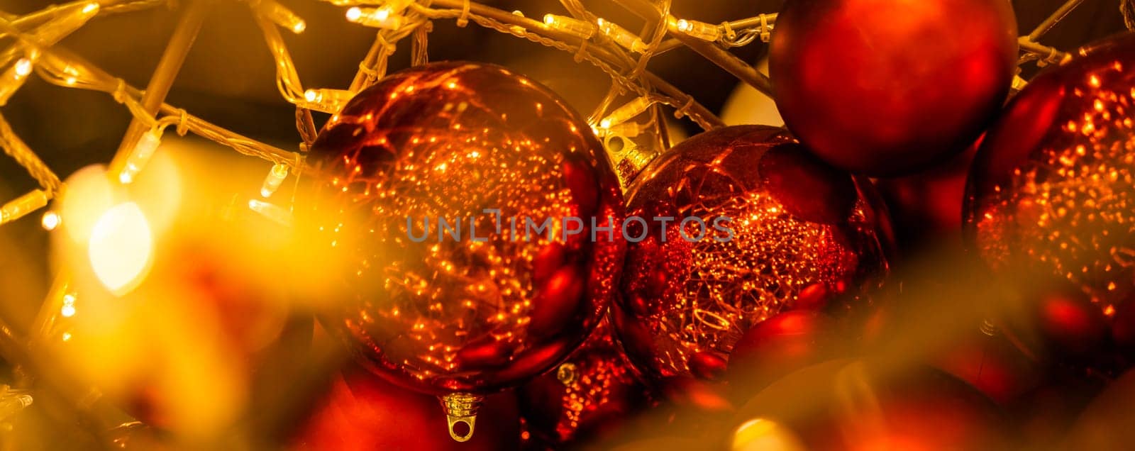 Red glowing Christmas balls garlands close-up. Holidays decoration and festive xmas concept. Copy space and empty place for text, mock up greeting card.