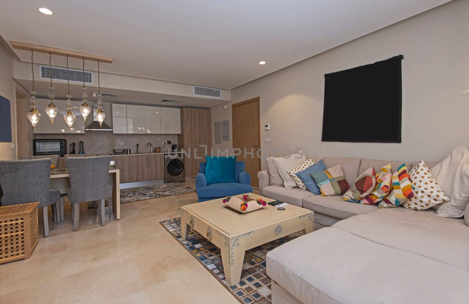 Living room lounge area in luxury apartment show home showing interior design decor furnishing with open plan kitchen