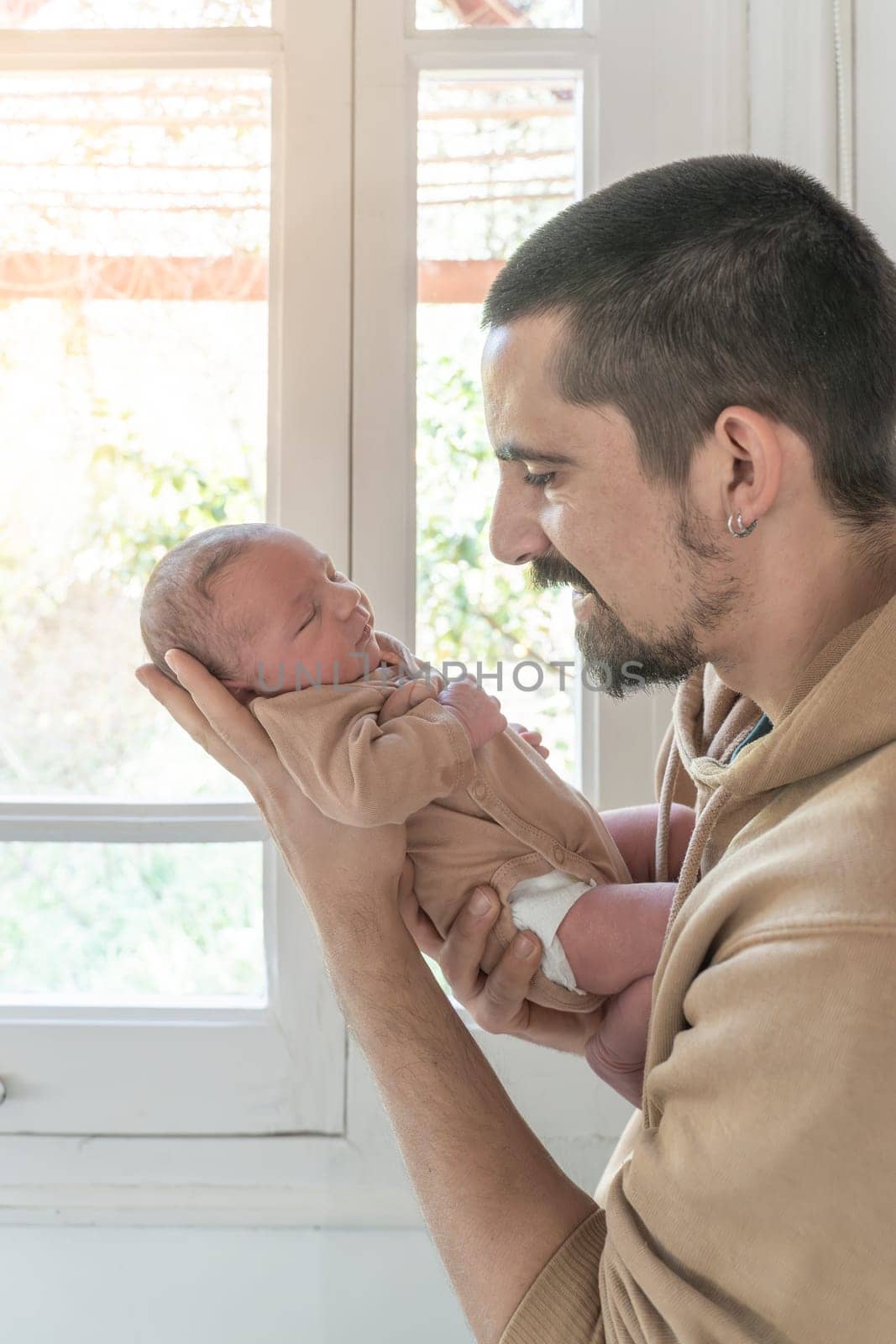 Smiling father and his newborn daughter, a couple of hours old. High quality vertical photo