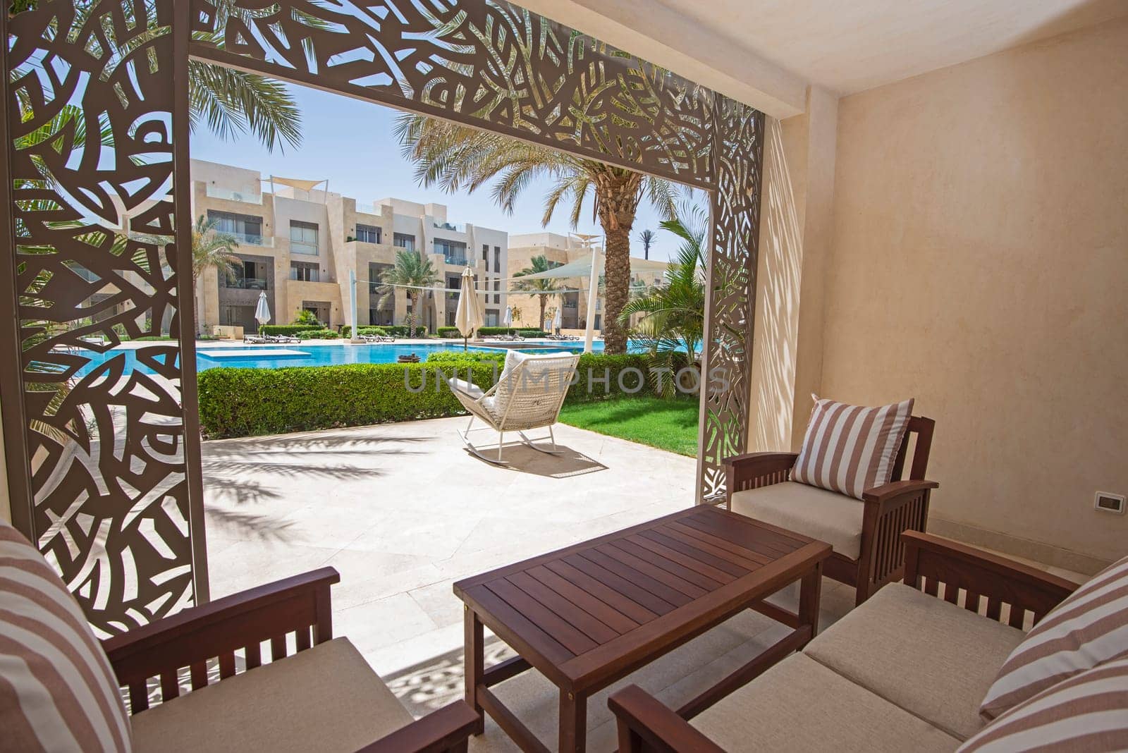 Garden patio terrace of a luxury apartment home in tropical resort with furniture and swimming pool view