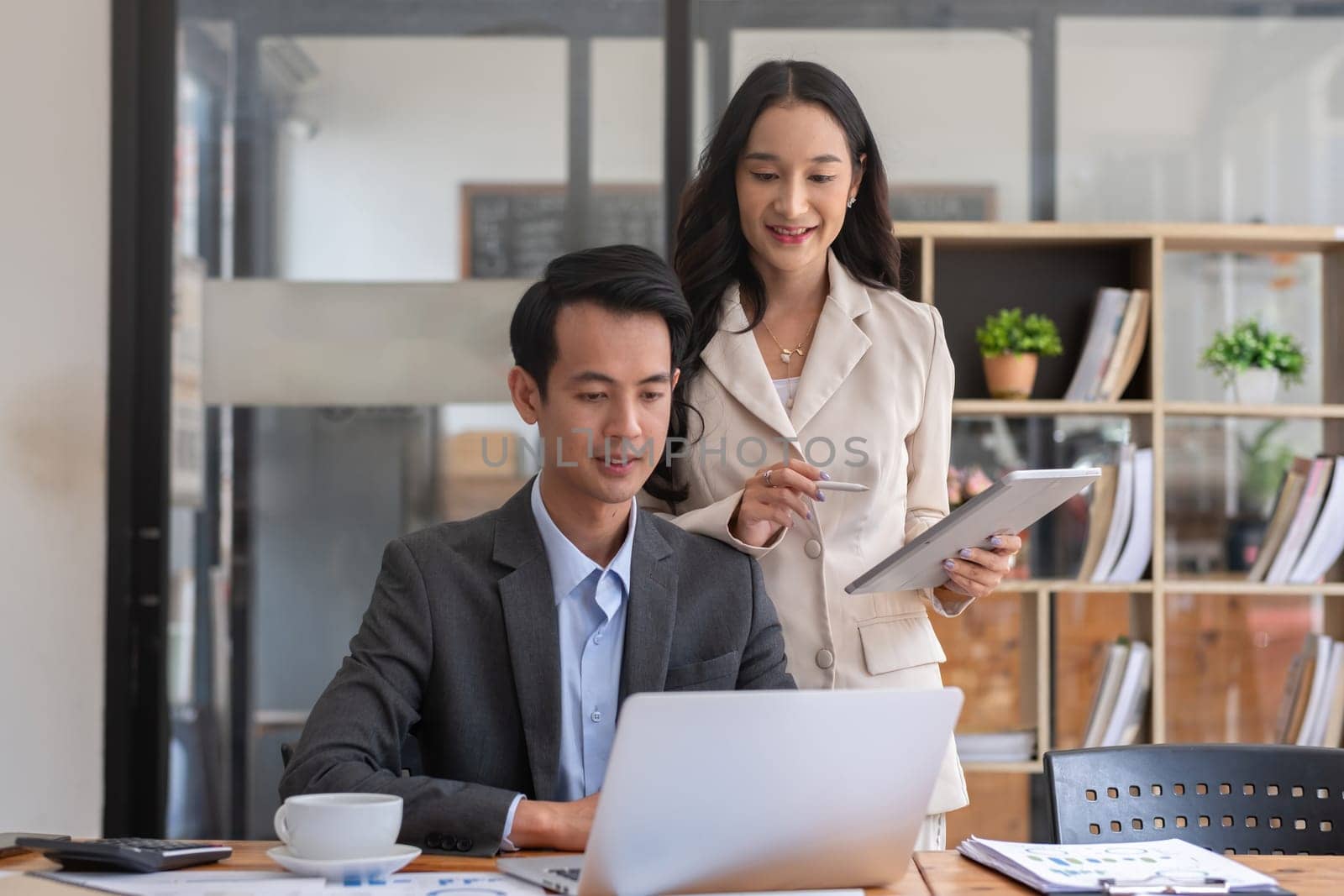 A young businessman and a female Asian accountant are discussing financial accounting and business planning together in the office..