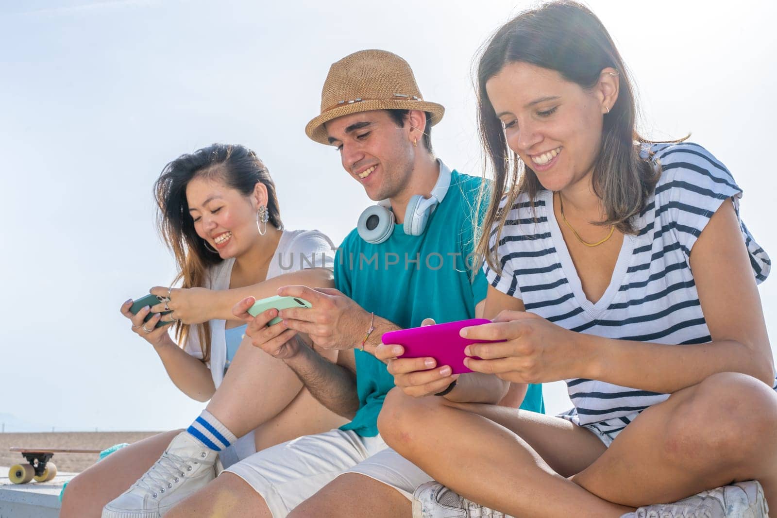 Multicultural group of trendy young friends having fun using smartphones and social media. Mobile games. by PaulCarr