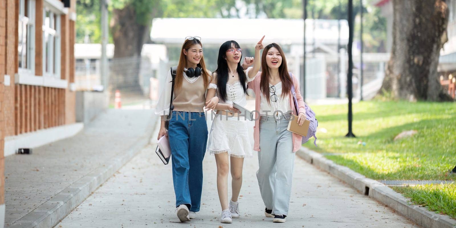 College friends walk to class together. University student in campus talk and have fun outdoors.