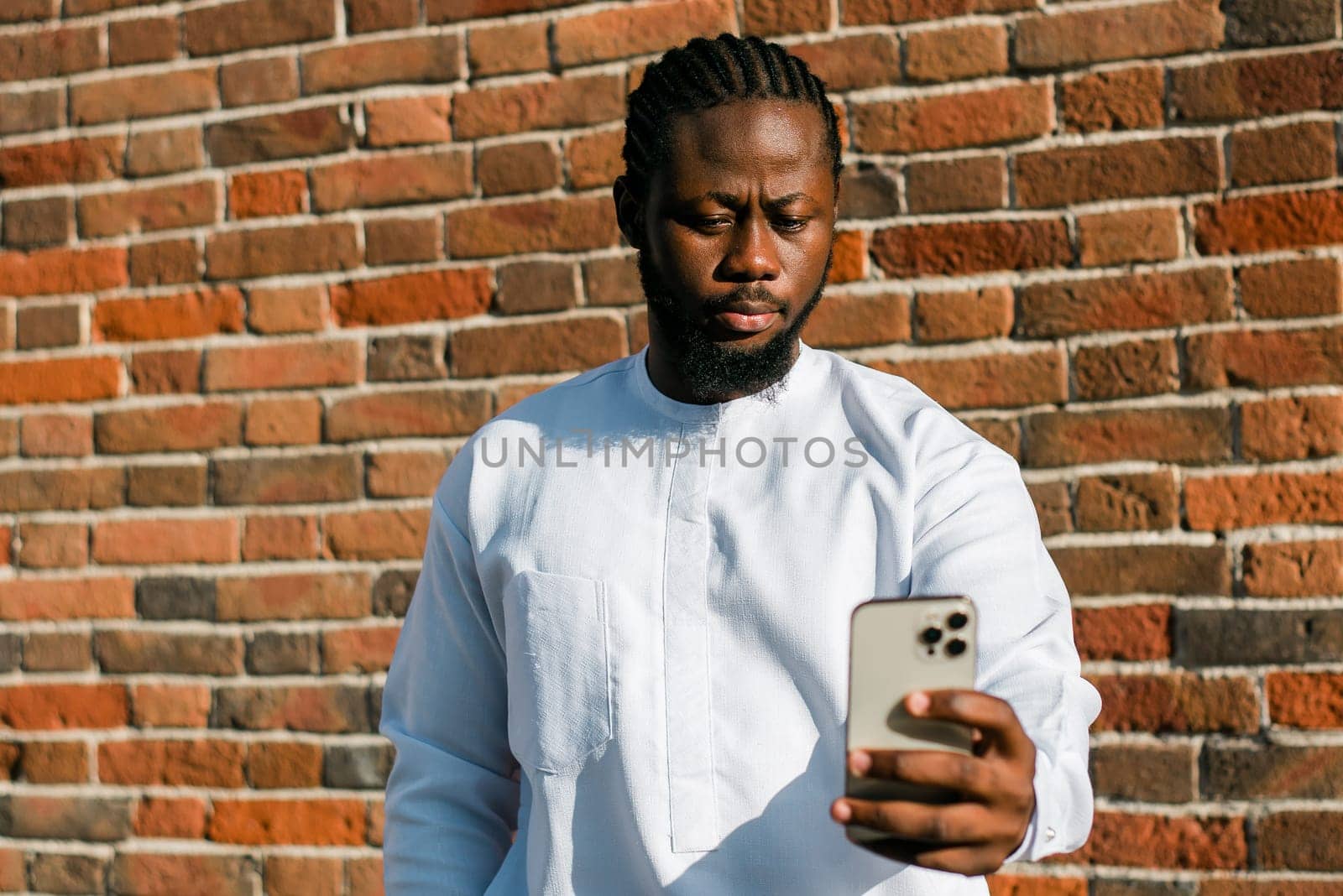African american man checks cell phone in the street in summer day. Millennial generation and gen z people. Social networks and dating app concept by Satura86