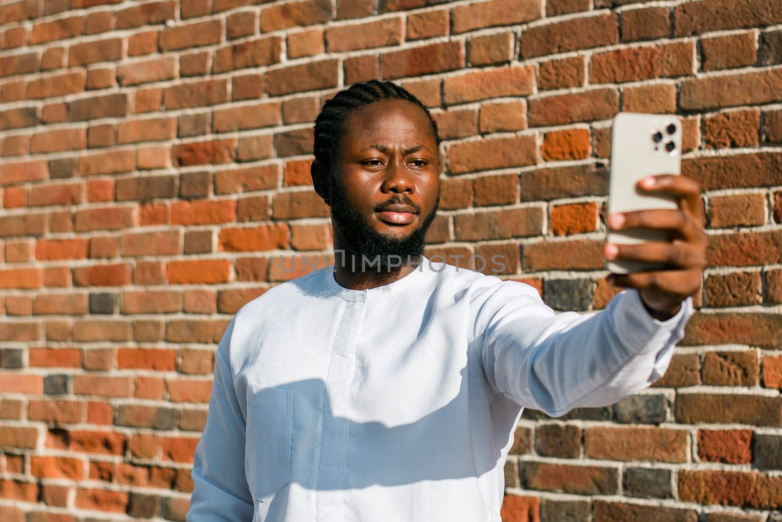 African american man checks cell phone in the street in summer day. Millennial generation and gen z people. Social networks and dating app concept by Satura86