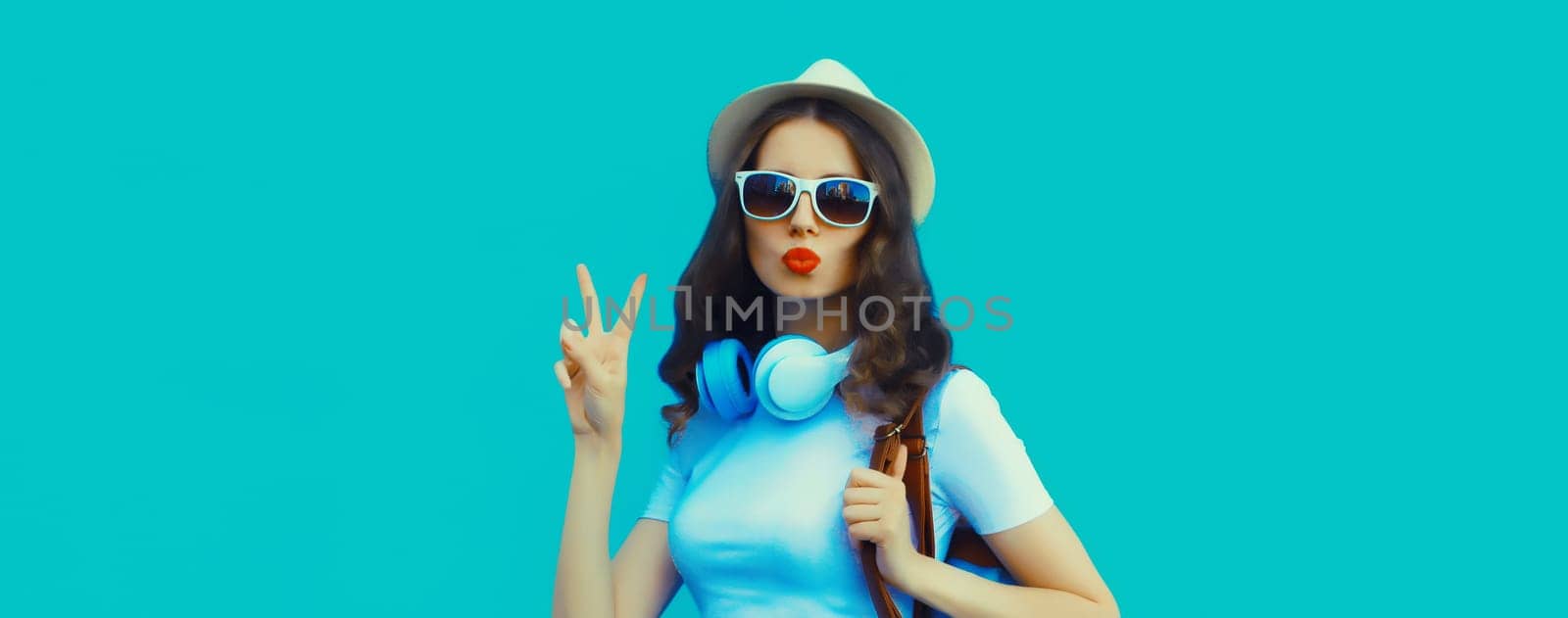 Happy modern happy young woman listening to music with headphones on blue studio background