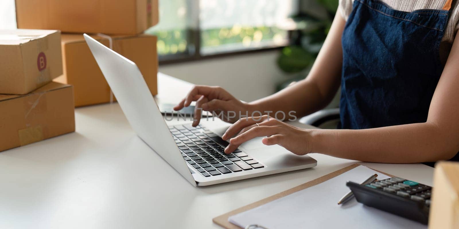 Woman in an online store check the customer address and package information on the laptop. Online shopping concept.