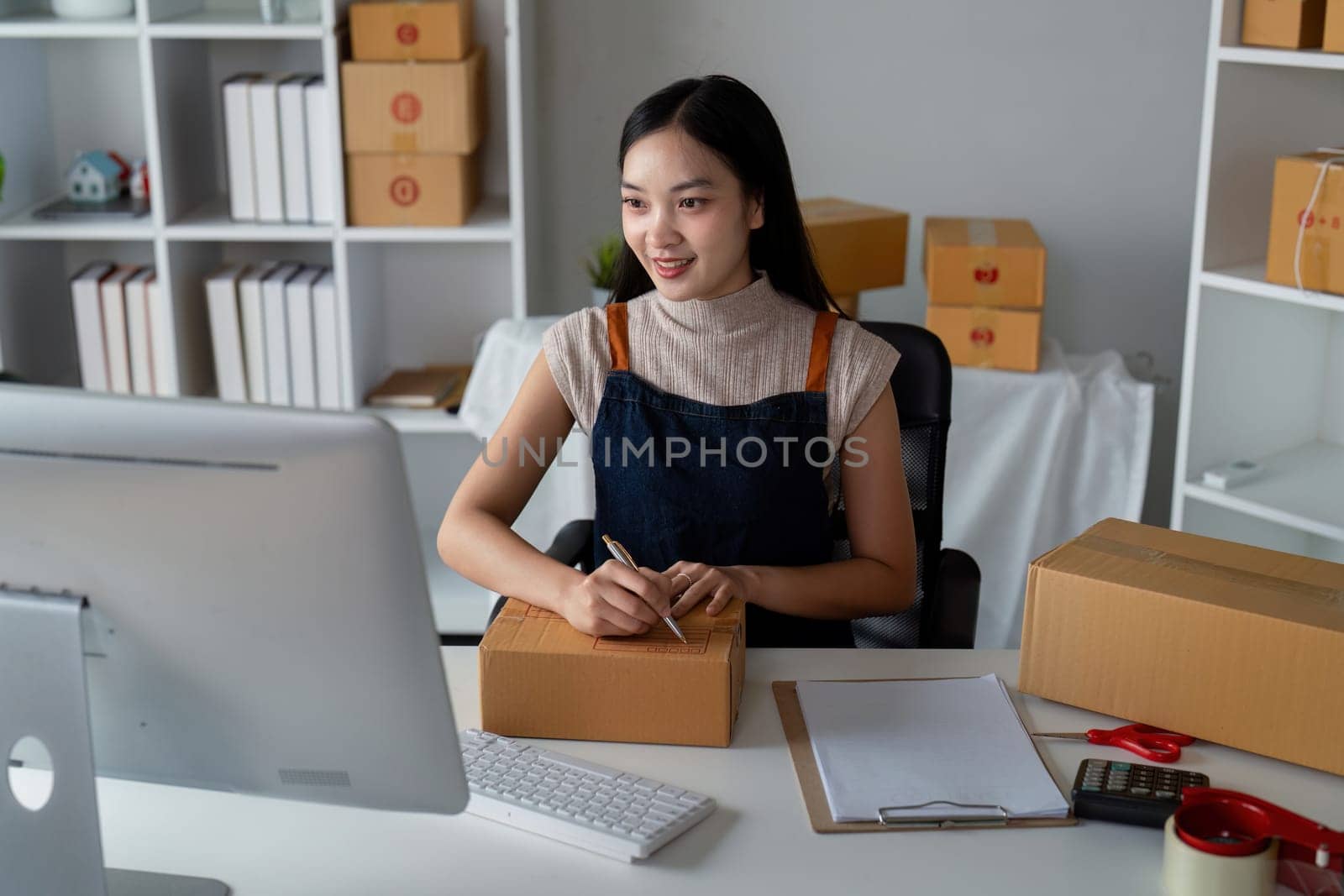 Woman asian in an online store check the customer address and package information on box. Online shopping concept.
