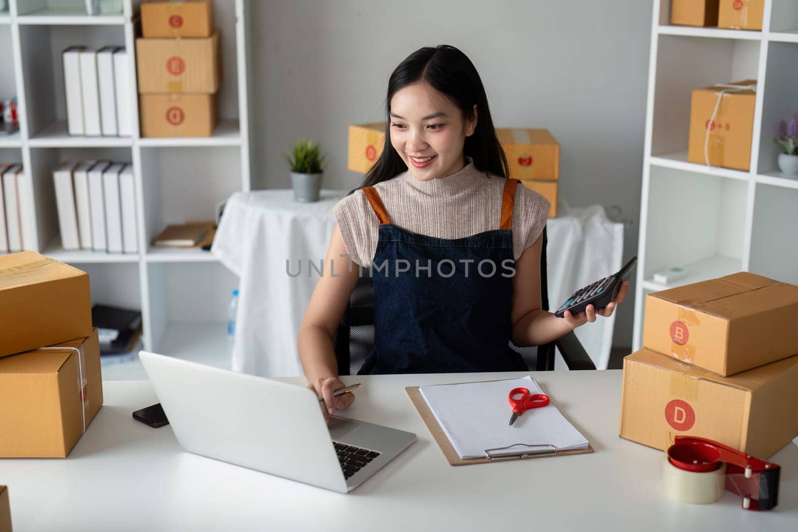 Startup small business entrepreneur of freelance Asian woman using laptop and box to receive and review order online to prepare to pack sell to customer, online business ideas by nateemee