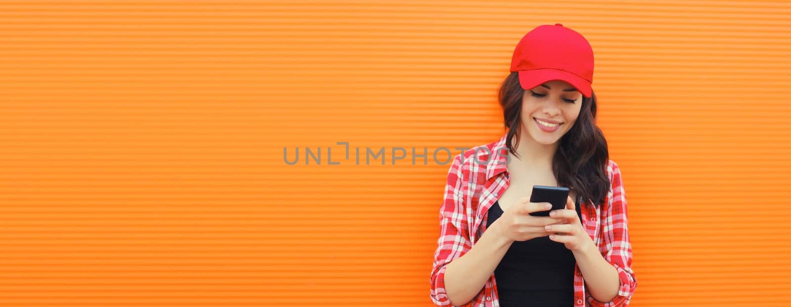 Portrait of happy smiling young woman with mobile phone on orange background by Rohappy