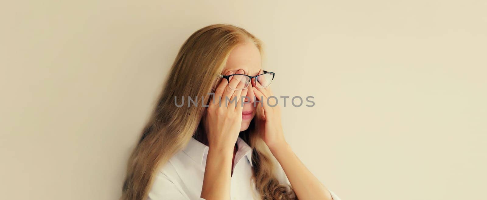 Tired overworked woman employee rubbing her eyes suffering from eye strain, dry eye syndrome or headaches after working at the computer