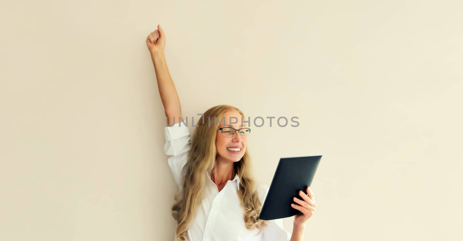 Happy joyful mature woman employee with tablet computer celebrates victory, feels success by Rohappy