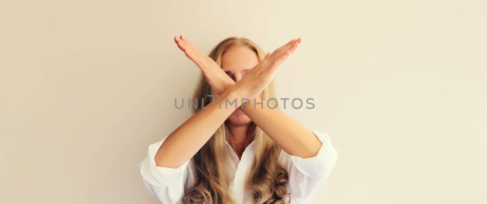 Upset woman shows stop, no or enough sign with palm of hand, refusal gesture, domestic violence by Rohappy
