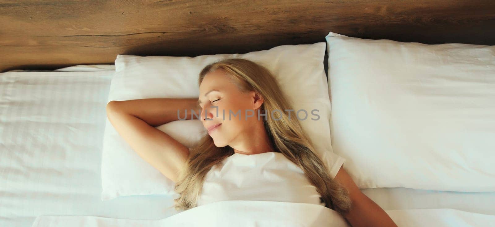 Woman sleeping lying in bed on white soft comfortable pillow in bedroom at home