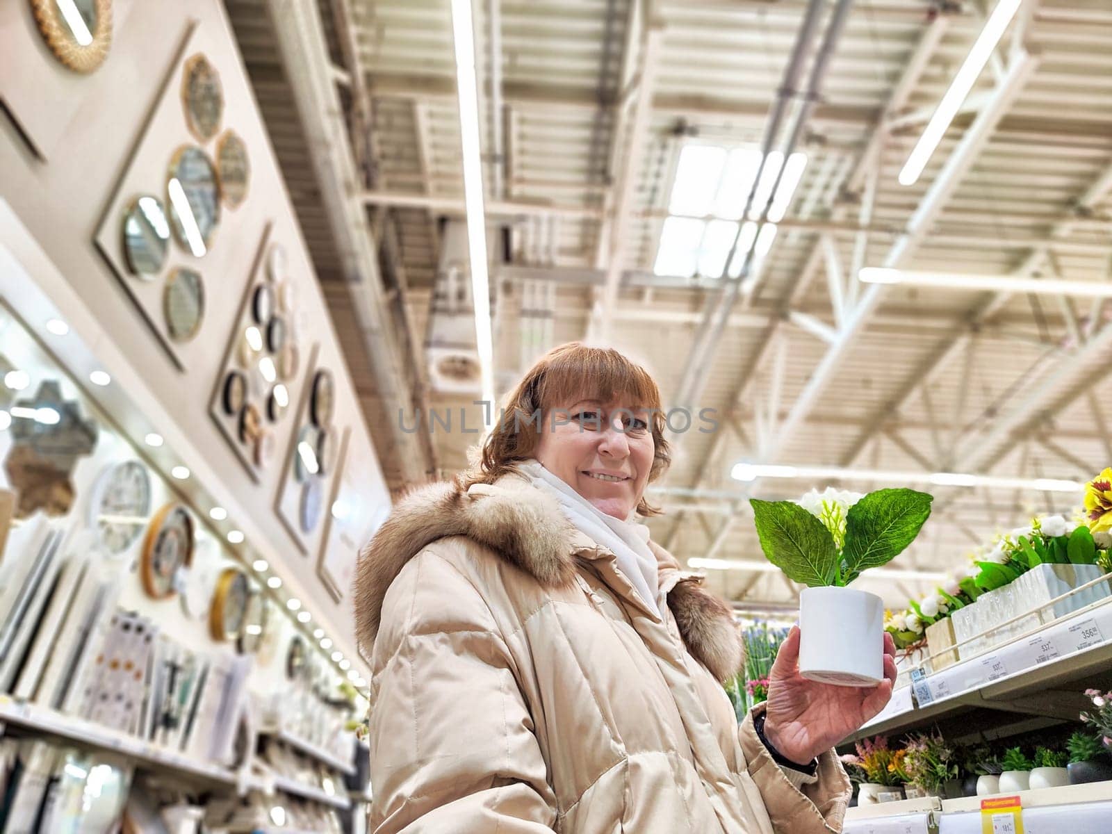 Middle-Aged girl in a flower and plant shop. Mature Woman Shopping for Seedlings at Plant Nursery in Spring