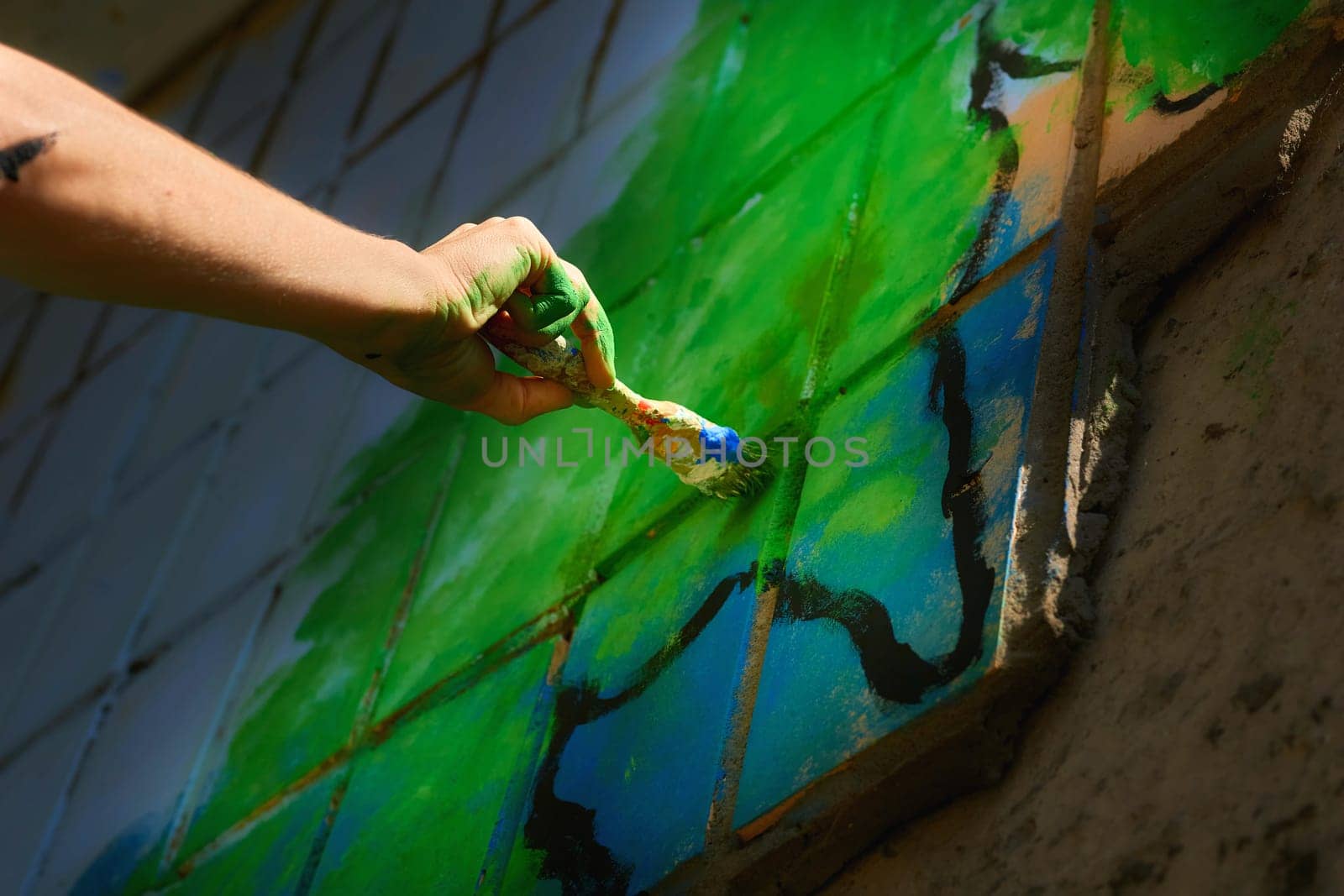 Female artist's hand with a brush painting graffiti on the wall by jovani68