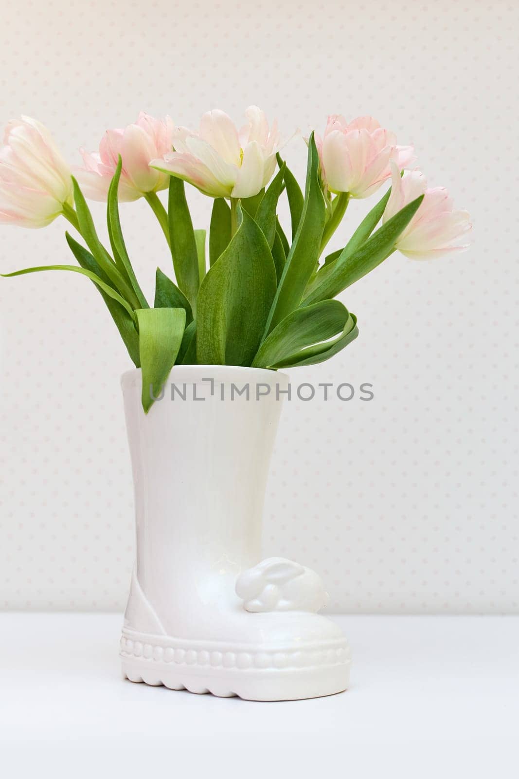 bouquet of tulips in Easter bunny vase on white table. copy space