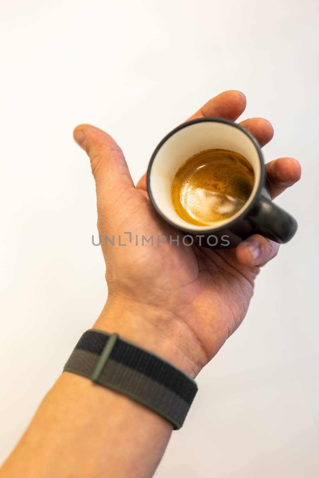 Close-up view of a freshly made espresso held in a person's hand.