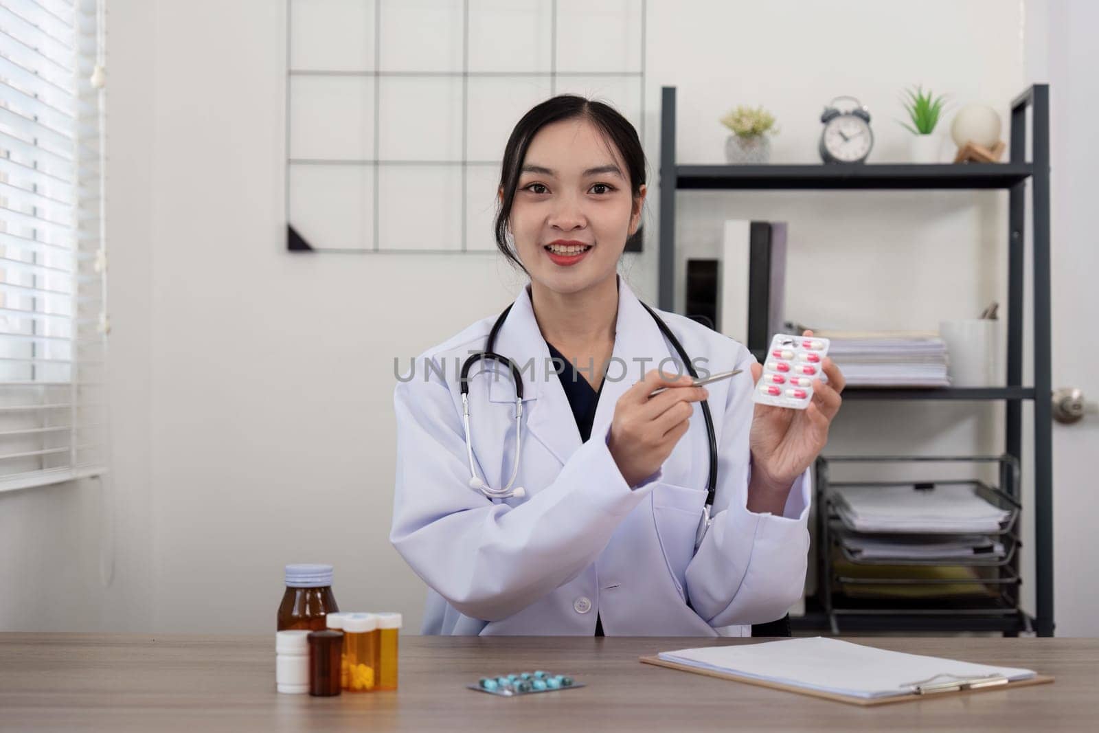 Doctor woman wearing white coat stethoscope on shoulders looking at camera, doctor make video call interact through internet talk with patient provide help online counseling and therapy concept.