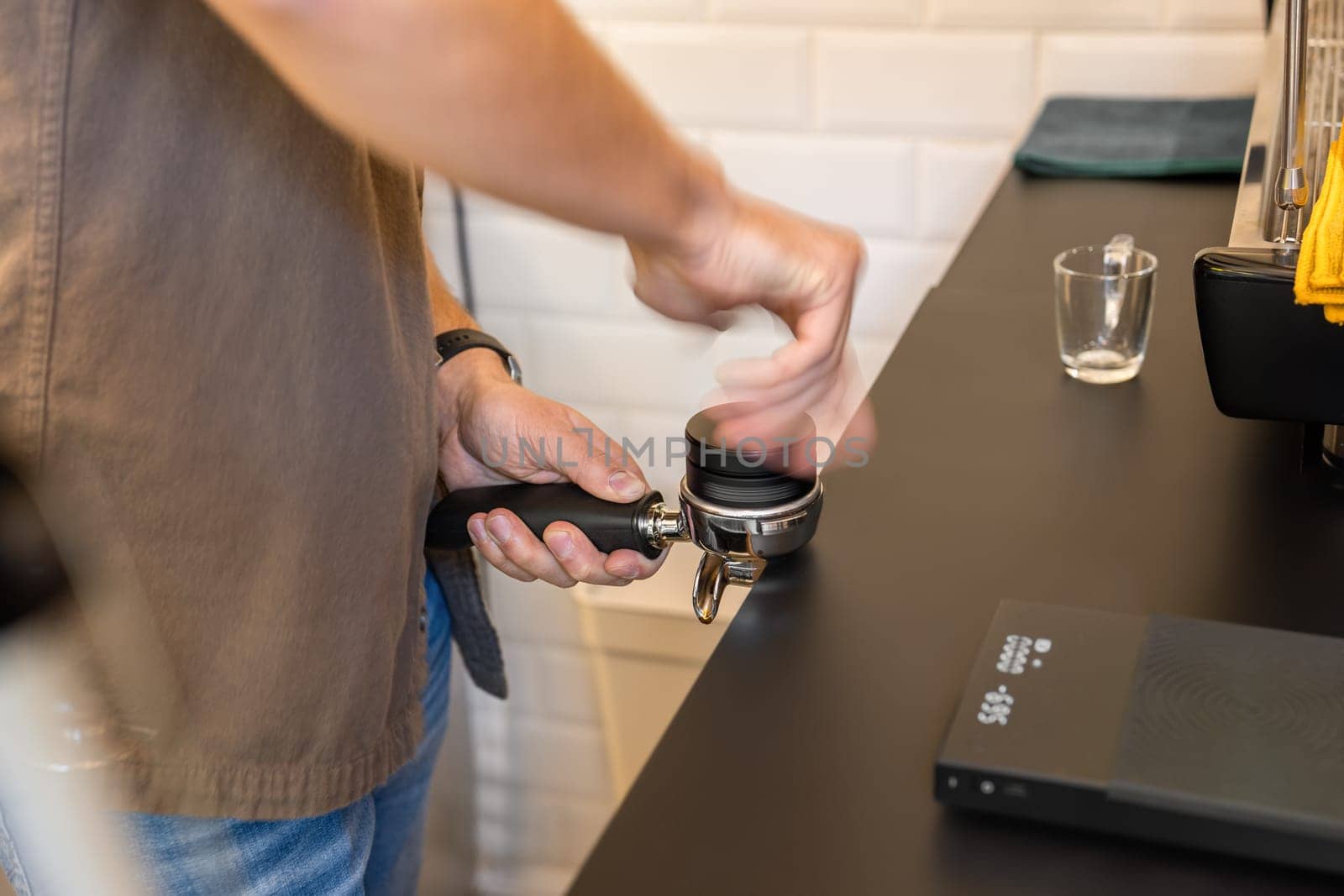 Barista hands expertly attaching a portafilter to an espresso machine by apavlin