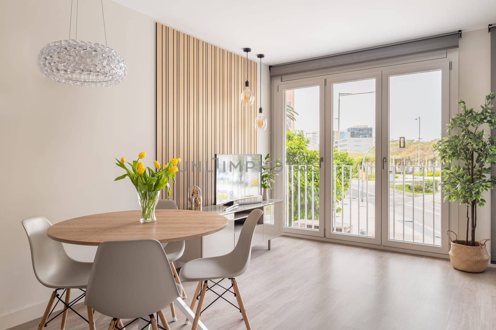 A contemporary dining room bathed in natural light, featuring stylish furnishings and a decorative light fixture.