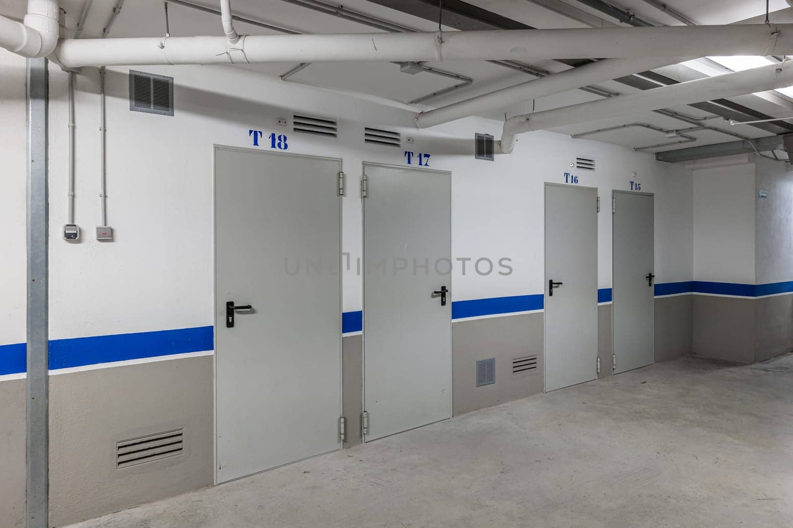 Modern storage facility with numbered white storage doors and blue stripes by apavlin