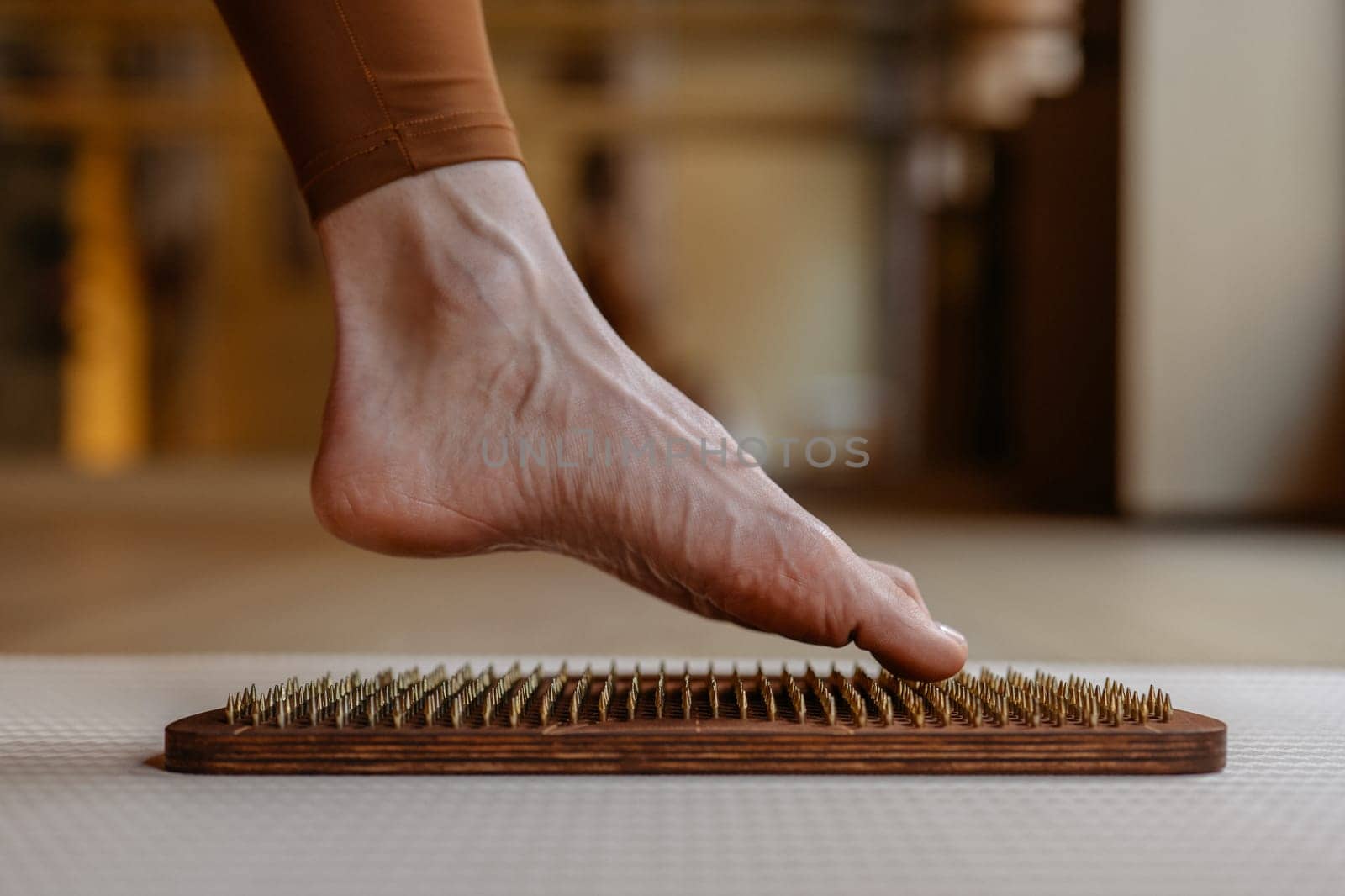 The contours of a foot exploring the sharp sensation of wooden pegs on an acupressure board.
