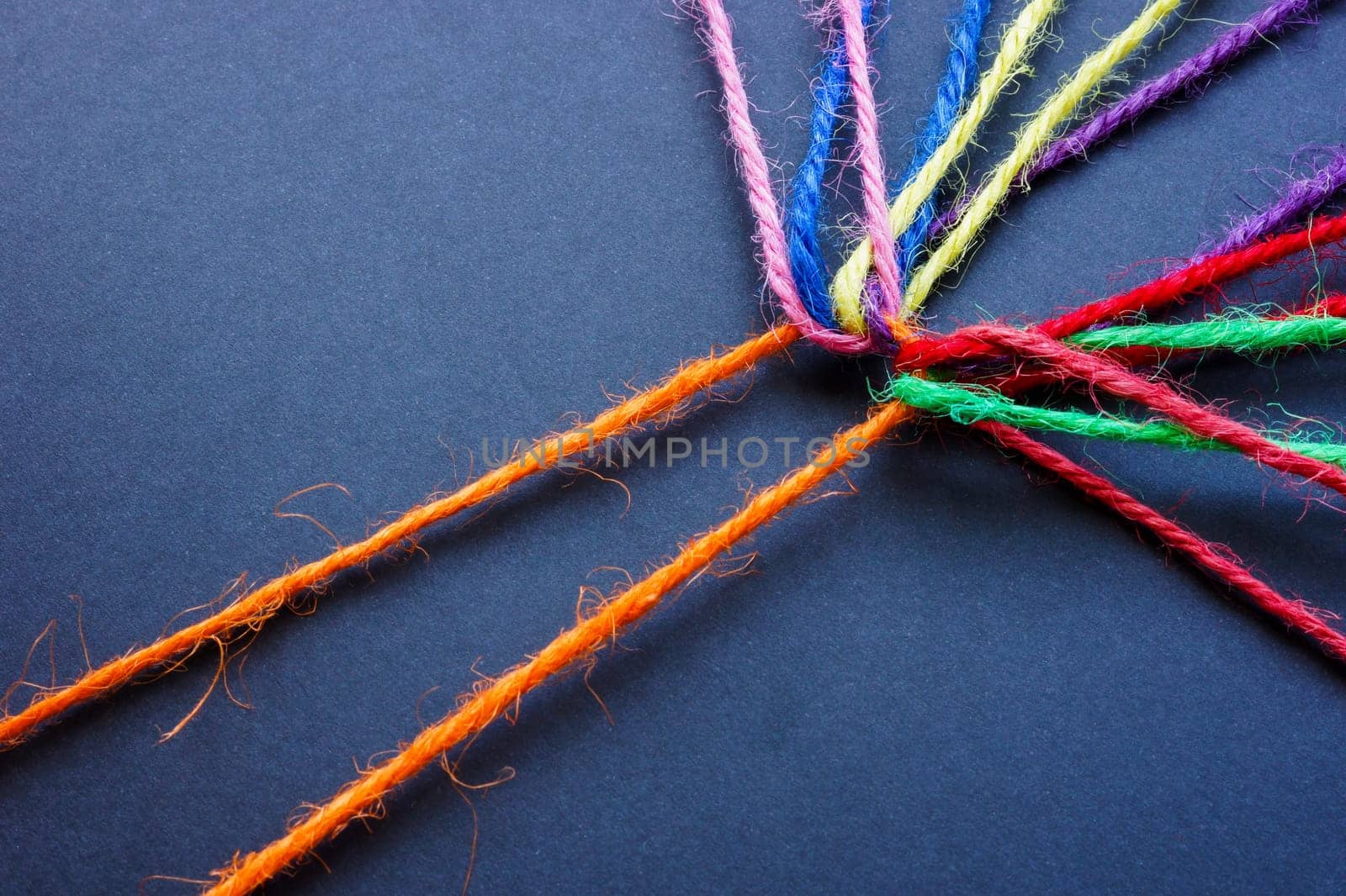 Orange thread connecting colored threads. Teamwork and diversity. by designer491