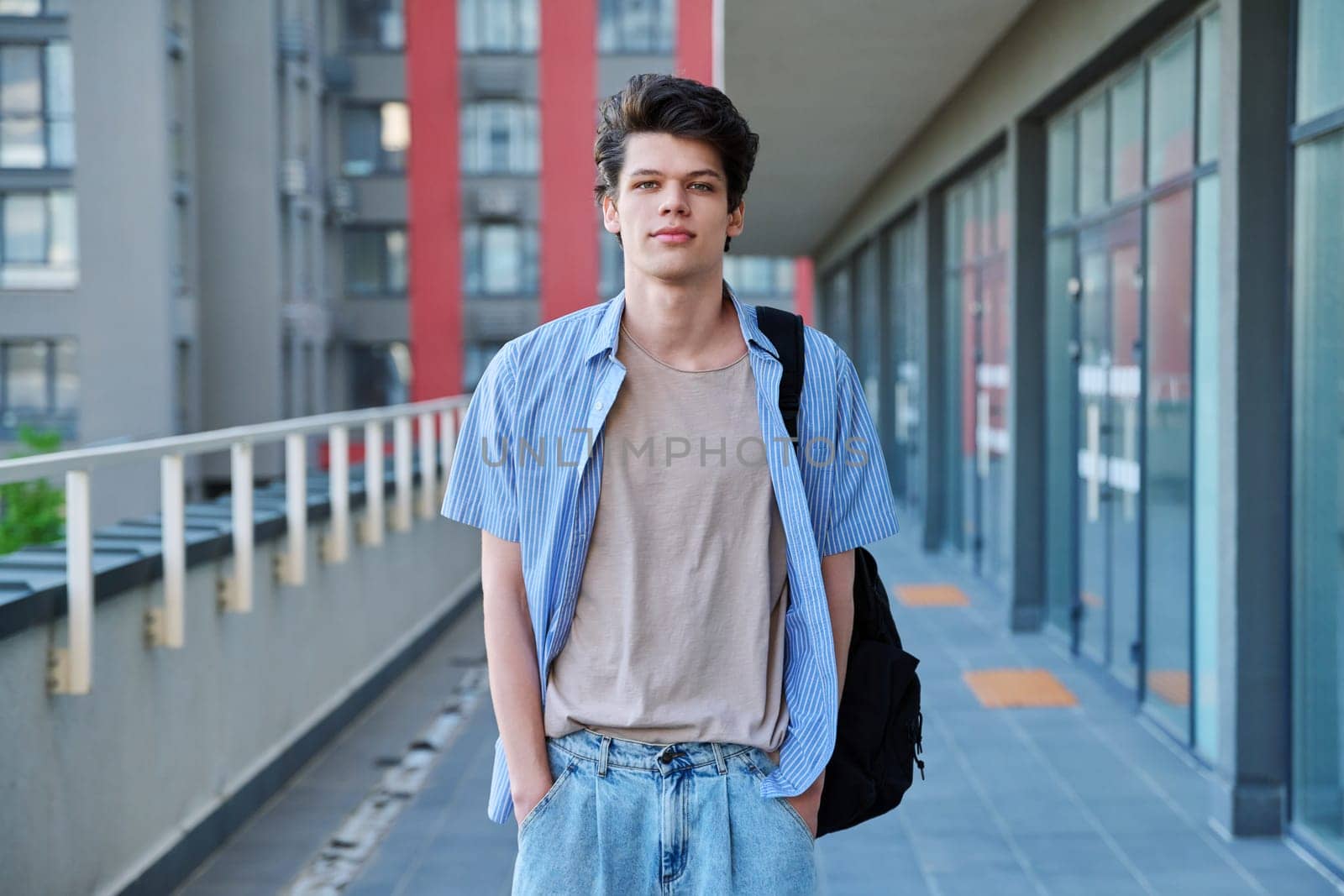 Portrait of confident smiling college student guy, young male with backpack looking at camera, urban outdoor. Education, lifestyle, 19,20 years age youth concept