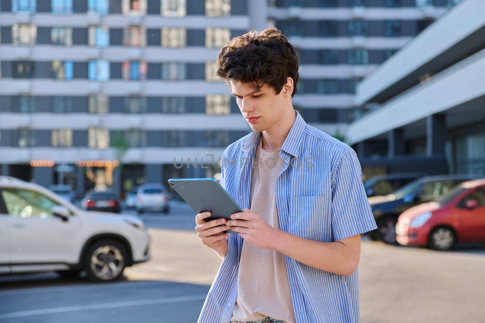 Young handsome male using digital tablet on city street by VH-studio