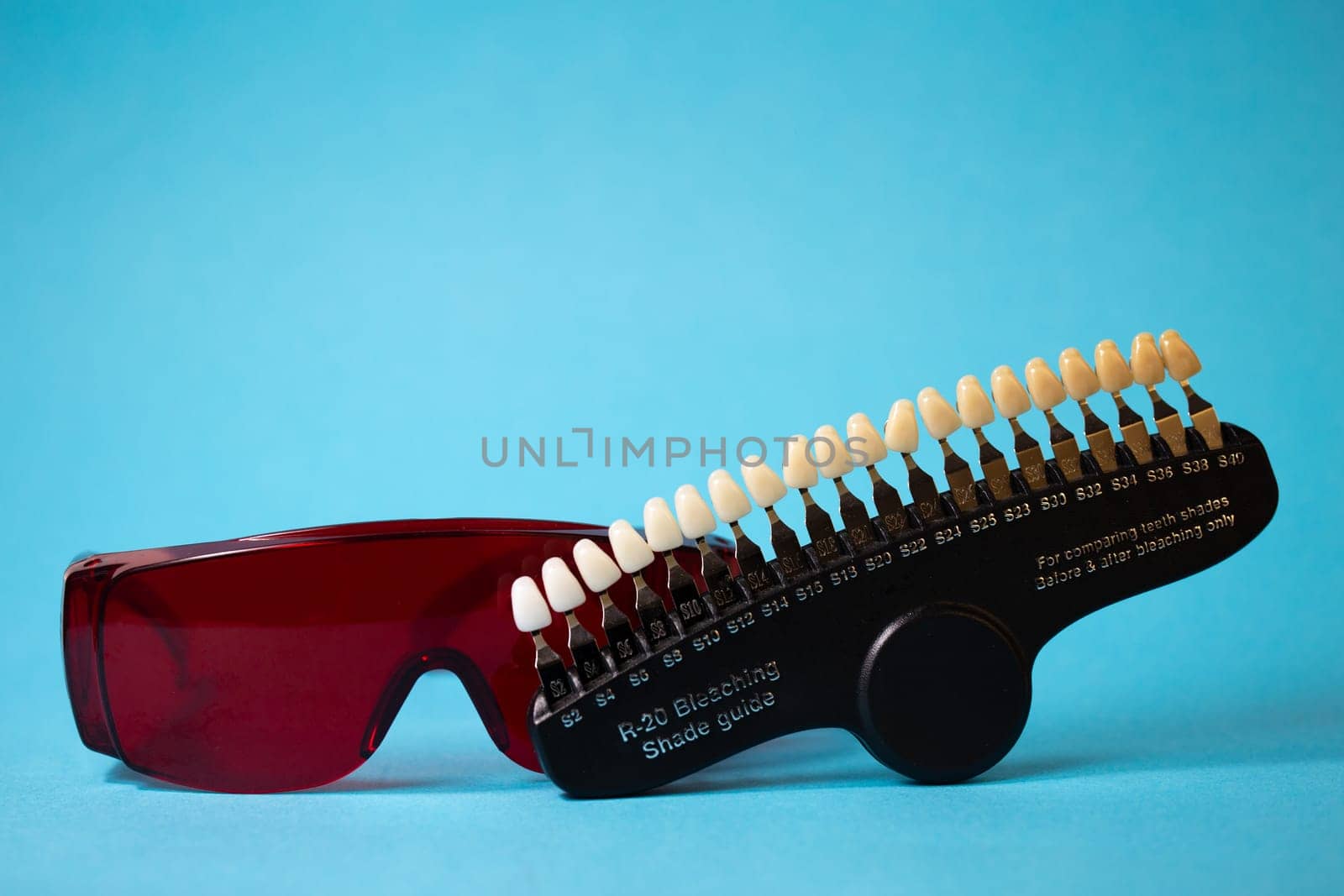 Dental equipment for the selection of the shade and color of teeth in close-up on a blue background.