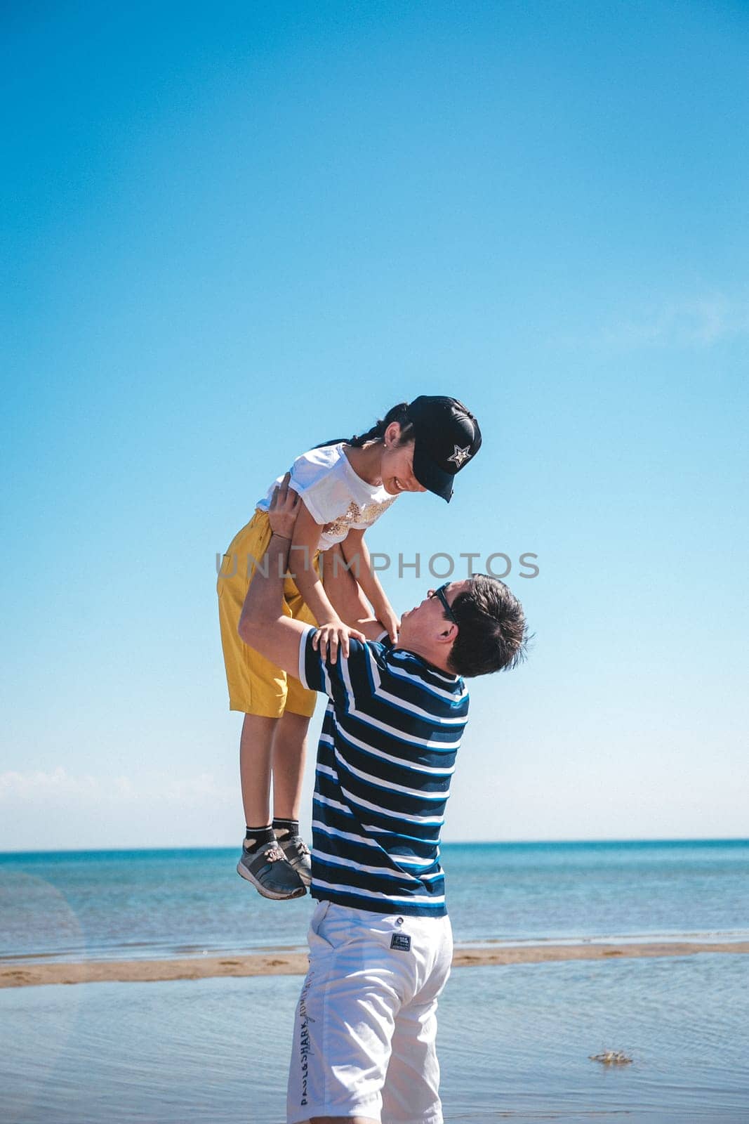 happy girl against the sky, dad tosses his daughter and catches her. Blue sky background. Sea, vacation and travel. Family day