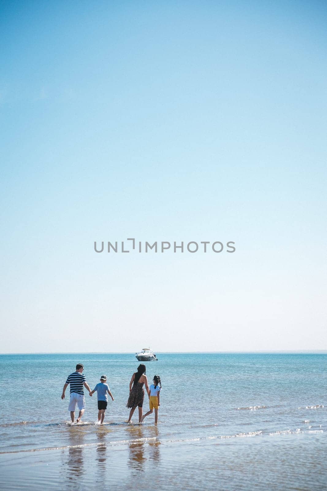 family walks on the sea, foursome mom dad son and daughter.